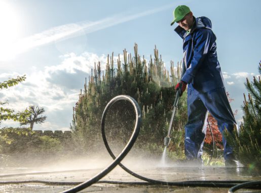 Garden Washing Maintenance. Caucasian Worker in His 30s with Pressure Washer Cleaning Brick Paths.